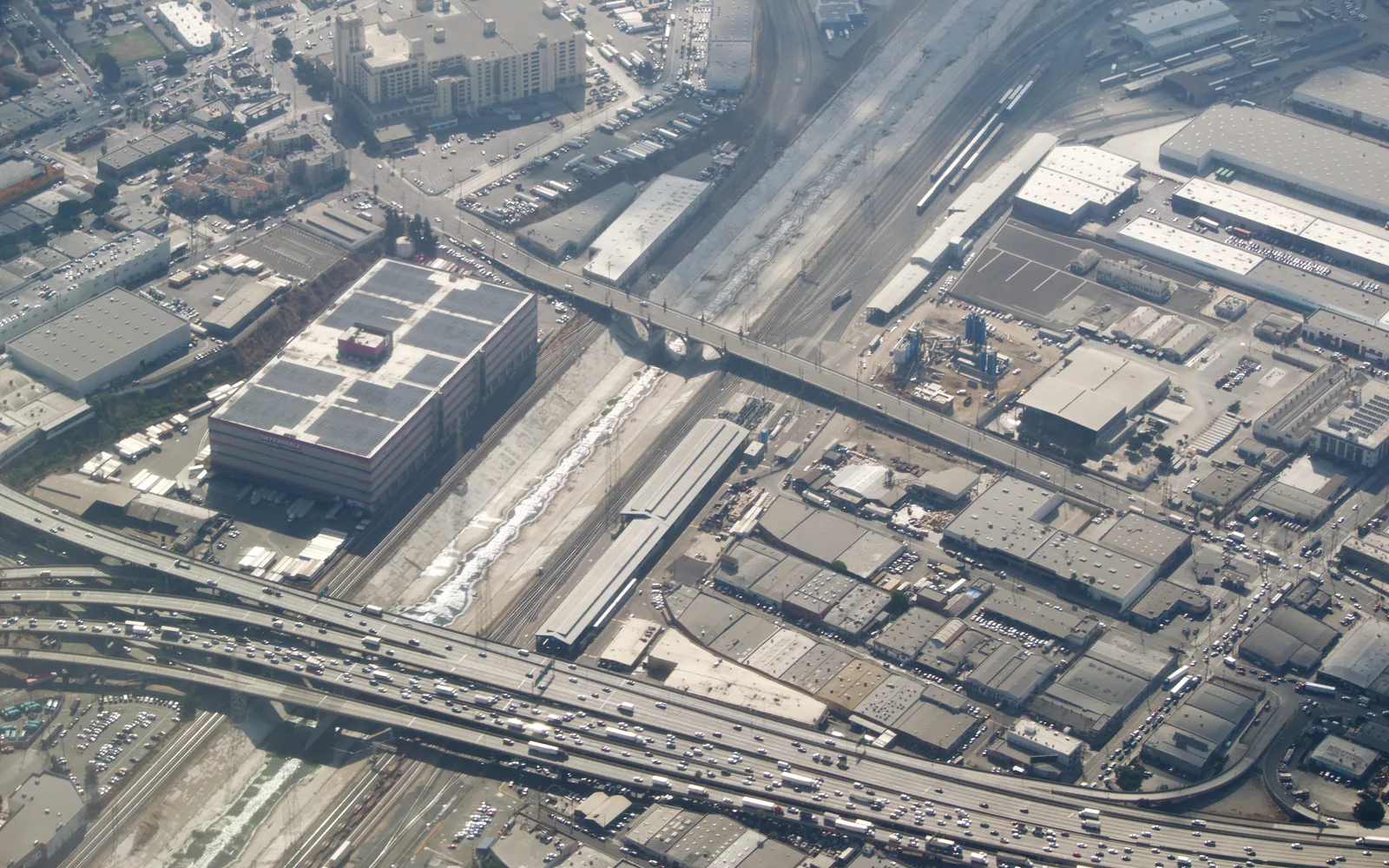 Aerial view of the Los Angeles River meeting multiple freeway interchanges in an urban landscape